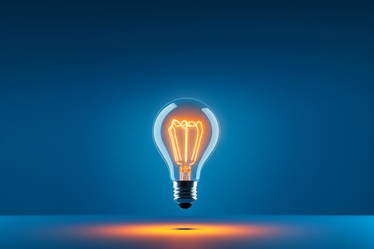 Isolated classic light bulb shining on blue background. Energy saving concept.