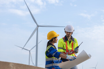 Wind turbine technician checking and maintenance at turbine station. Man and woman engineer working at energy wind generator. clean energy source.