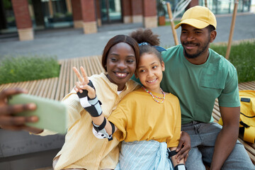Obraz premium African American family making selfie portrait on smartphone during their walk outdoors