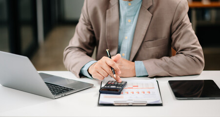 Close up of businessman or accountant hand typing laptop working to calculate on desk about cost at modern office..