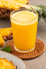 Fresh delicious pineapple juice smoothie in glass cup on gray table background.