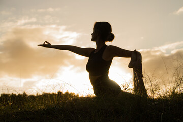 Silhouette of woman making yoga at the sunset