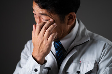 悲しんでいるミドル男性　作業服イメージ