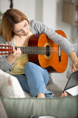 Fototapeta premium casually dressed woman holding guitar and touching tablet screen