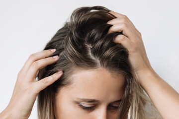 Cropped shot of a young caucasian blonde woman with dirty greasy hair on a white background. The problem of oily scalp. Itching of the skin from long non-washes of the head - obrazy, fototapety, plakaty