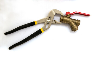 A brass water faucet with a filter and a red handle is clamped in the jaws of an adjustable wrench with black rubberized handles