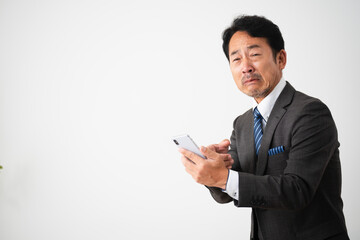 スマートフォンを持って悲しんでいるミドル男性　ビジネスイメージ
