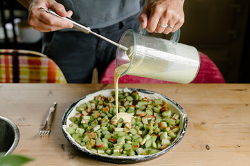 Unrecognizable man baker standing near pie dough and ingredients pan and pouring sauce from glass jar