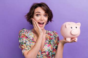 Photo portrait of pretty young girl excited hold piggy ebanking wear trendy flower print outfit isolated on violet color background