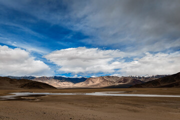 Silently coursing through the barren valley of Ladakh, the Indus River offers a haven of calmness. With barren mountains standing in the distance, the river's tranquil waters mirror the azure sky.