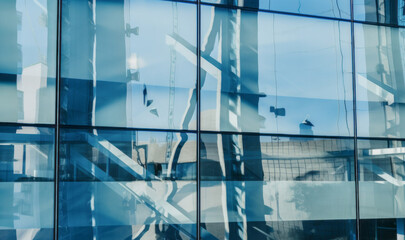 Obraz premium Reflections in an office building window of modern steel construction in an urban city environment.