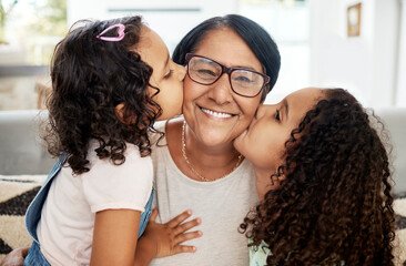 Children kissing their grandmother on her cheek with love, care and happiness in the living room. Happy, smile and portrait of senior woman hugging her girl kids in the lounge of the family home.