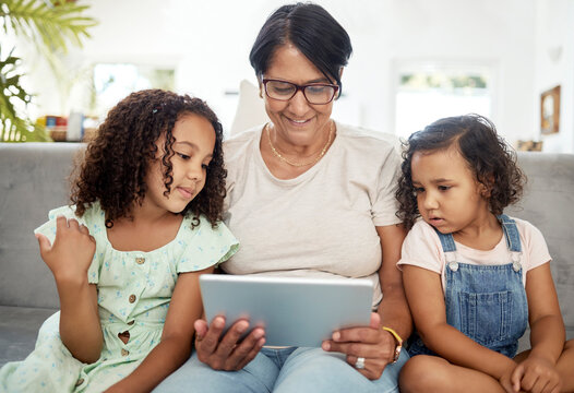 Tablet, bonding and grandmother watching with children enjoying a video or movie together in the living room. Happy, smile and kids streaming a show on digital technology with a senior woman at home.