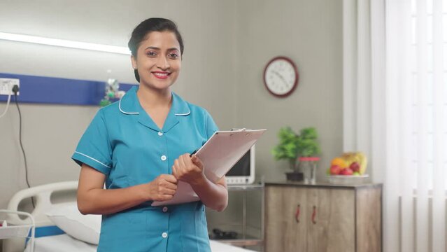 Happy Smiling Nurse with Clipboard standing confidently by looking camera at hospital - Concept of professional occupation, Medical Profession and Career Success