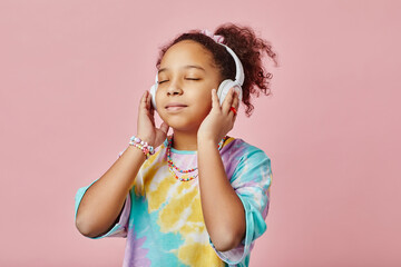 Pretty girl listening to healing or relaxation music in headphones while standing in front of camera and posing during photo session