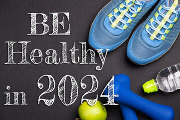 New year 2024 resolutions healthy lifestyle and sport. Be healthy in 2024. Motivation sport goals 2024 with sport equipment shoes, dumbbells, fruit and water bottle on black background
