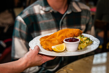 Kellnerin serviert Mann ein Schnitzel mit Beilagen im Restaurant 