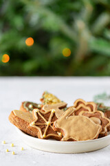 Homemade gingerbread cookies with honey, cinnamon and spices in a plate on the background of a Christmas tree.