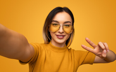 Positive woman in glasses showing two fingers