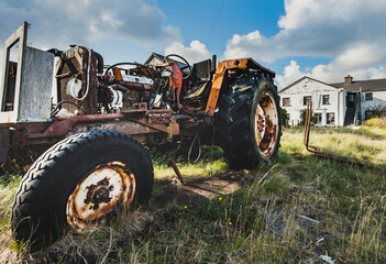 Old tractor with missing body parts as rusty engine and mechanical parts are visible. Forsaken agricultural vehicle conveys the decline of the cultivation and rural depopulation. Cannibalised tractor