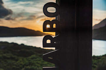Detail of Killary Harbour sign at sun set with the ocean in background. Killary Fjord sign with the...