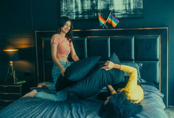 Lesbian partners' indoor pillow fight strengthens romance, and fills the room with affectionate.