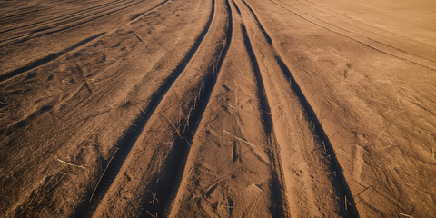 Sand background, sandy waves on windy day on the beach or in desert, natural background. Strong wind on the beach, sand storm. Sand is flying in the face. Tire tracks on a sandy beach.
