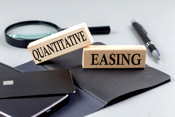 Quantitative Easing text on a wooden block on black notebook , business concept