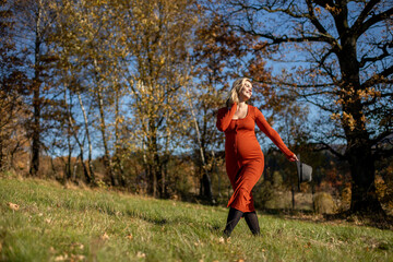 Happiness concept pregnant woman walking on grass field