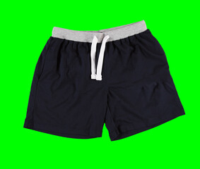 Folded men's shorts on a green background. Isolated image on a green background. Nobody. 