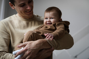 Man holding little five, six months baby smiling at home. Father and child indoors, Happy parent kissing his child.Copy space.