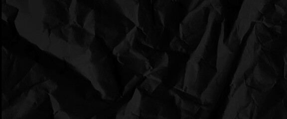 Fototapeta premium Texture of black crumpled paper, black crumpled paper texture in low light background, dark paper background with chaotic bends, black wrinkled paper texture.