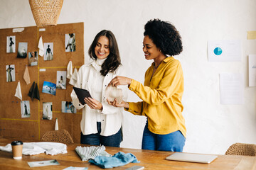 Female fashion designers presenting a sample of fabric to a client on a video call
