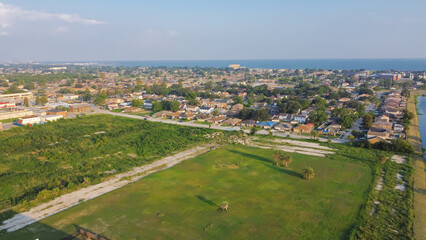 Fototapeta na wymiar Large vacant land near Farrar Canal with residential houses, duplex townhomes, lush green trees in Little Woods neighborhood toward Lake Pontchartrain in East New Orleans, Louisiana, USA