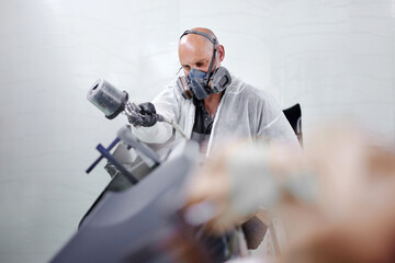 The painter's expert handiwork results in flawlessly painted car parts, ready to be assembled and enhance the vehicle's allure.