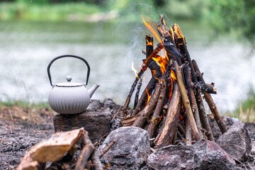Small kettle is heated on a bonfire, outdoor recreation concept.