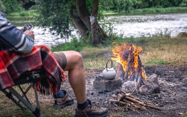 Man tourist sitting in touristic tent and using cell phone at evening time.