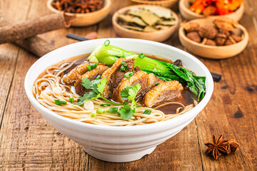Spicy red soup beef noodle in a bowl on wooden table