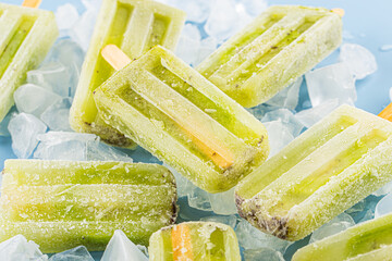 Kiwi ice cream popsicle on top of wooden board background