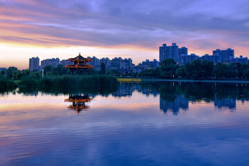 Fototapeta premium In the city park, the beautiful sunset reflects the cloudy sky and the river surface of the lotus pond