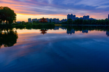 Fototapeta premium In the city park, the beautiful sunset reflects the cloudy sky and the river surface of the lotus pond
