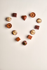 Heart shape made with various types of chocolate truffles over a white table