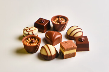 Heart shape made with various types of chocolate truffles over a white table