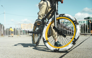 A boy in a cap and T-shirt rides a bmx bike and learns to perform tricks near a special ramp for...
