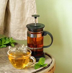 tea in a cup and french press on a wooden table