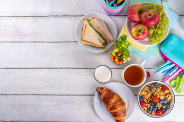 Healthy nutritious  morning breakfast for school kids, with fresh fruits, vegetables, croissant, muesli, milk and sandwich. Having breakfast before school and work, copy space
