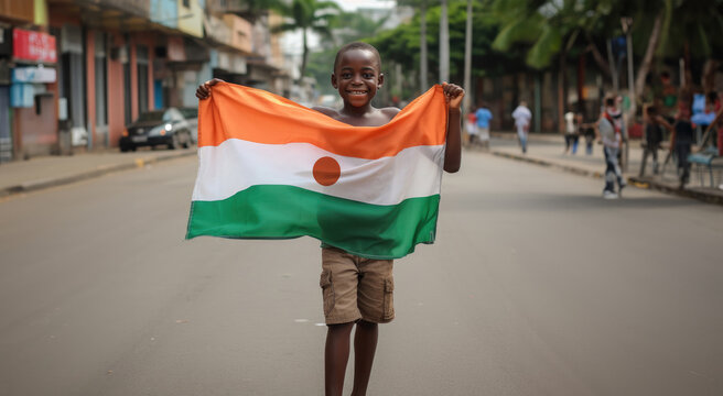 Un enfant nigérien tenant le drapeau de la république du Niger entre ses mains