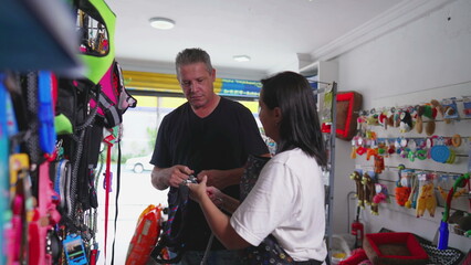 Man Shopping at Pet Shop. Female Business Owner Assists in Choosing Dog Leash