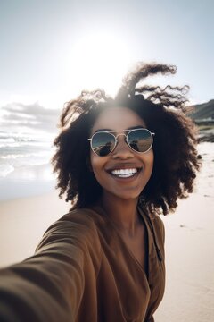 shot of a young woman using her cellphone while taking selfies at the beach