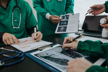 The medical team meets with doctors in surgical gowns sitting at a table discussing the patient's history. success of medical health care doctor work concept